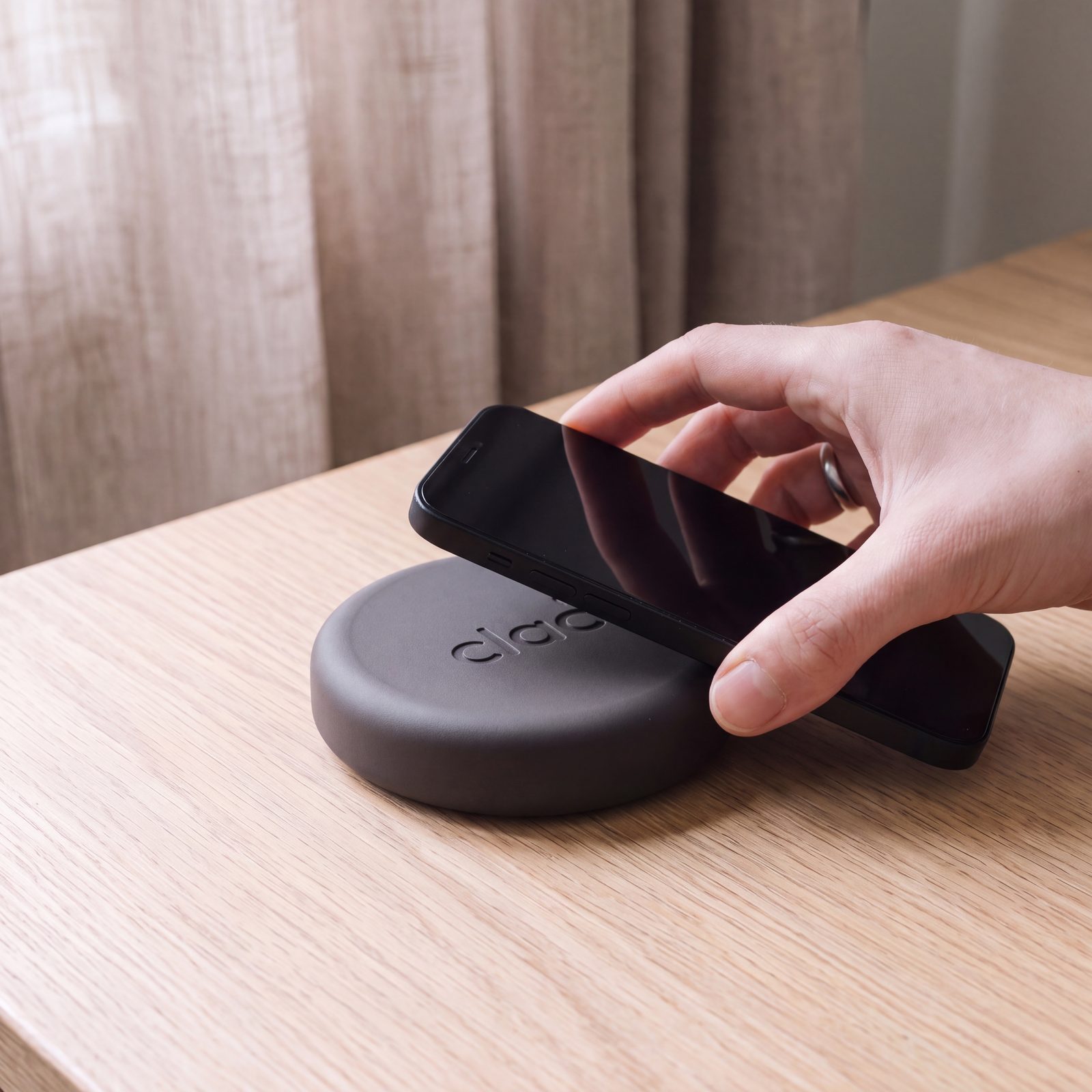 Le haut d'un iPhone touche le Clac posé sur une table claire